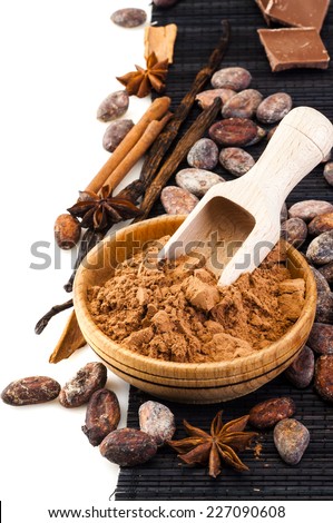 Cocoa powder in wooden bowl and scoop with cacao beans around