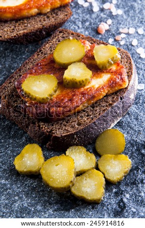 Rye bread sandwiches with fried halloumi cheese and pickles on gray stone background