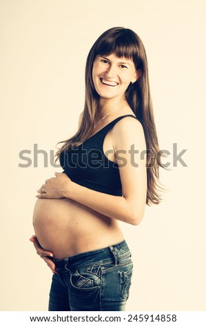 Happy smiling pregnant woman holding her belly