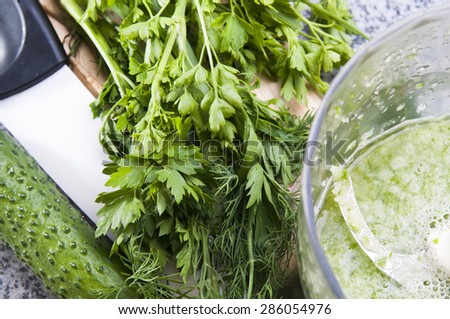 Blender is mixing a green smoothie. Close up of healthy fresh green vegetable smoothie from cucumber, dill and parsley on a marble table, top view