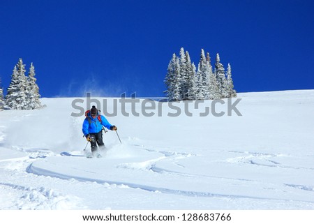 Man skiing powder snow on a bluebird day in the Utah mountains, USA.