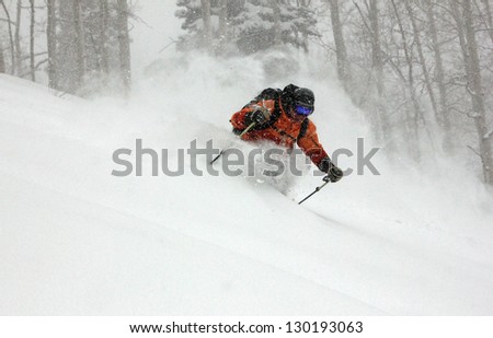 Man skiing deep powder snow during a blizzard in the Utah mountains, USA.