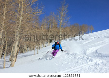 Woman skiing beside aspen trees in the Utah mountains, USA.