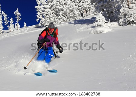 Smiling woman skiing fresh powder snow in the Utah mountains, USA.
