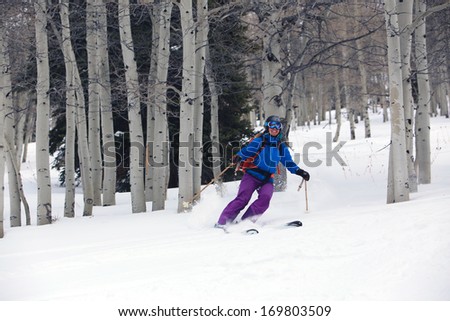 A smiling woman skiing in an aspen glade, Utah, USA.