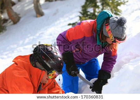 Ski guides dig snow pits to study snow layers, Utah, USA.