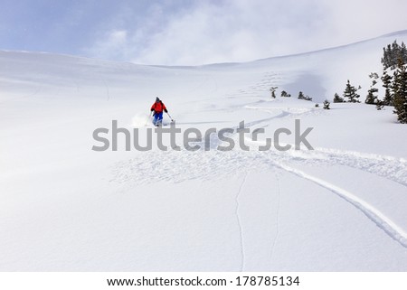 A woman skiing down a large open bowl in the Utah mountains, USA.