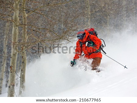 Skier in deep powder snow during a winter blizzard, Utah, USA.