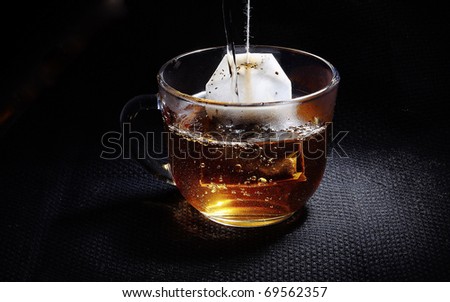 Glass cup on the table. Tea bag. Boiling water.