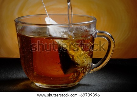 Glass cup on the table. Tea bag. Boiling water.