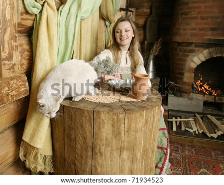 A young Russian woman in traditional Russian clothes. Interior of Russian country house.