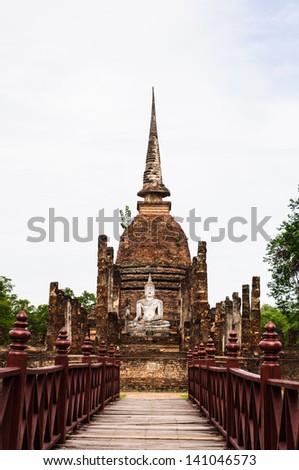 Wooden red bridge. Cross a pond to the temple in Sukhothai Historical Park, Thailand