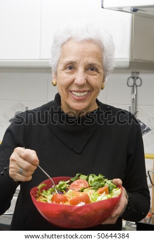 Senior woman eating a healthy salad at the kitchen