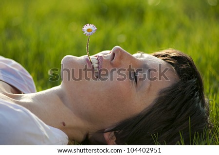 Young lady with flower in her mouth relaxing in springtime