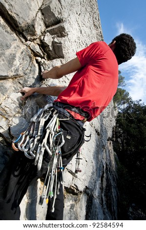 Man climbing on limestone with nuts, friends and carabiners, Muzzerone Mountain, Italy