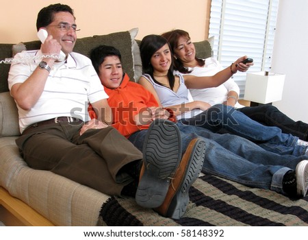 Family reclining in bed smiling at television