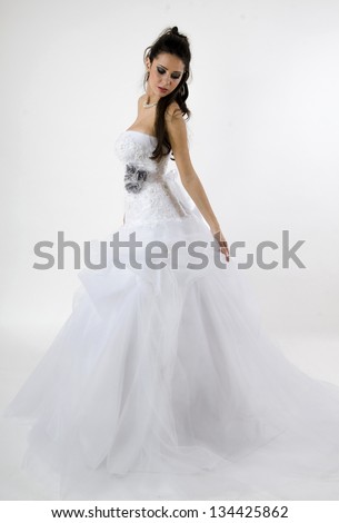 beautiful bride in wedding dress with a veil on her head standing and holding the wedding dress and looking down