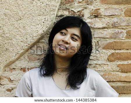 Asian woman wondering about something on brick background