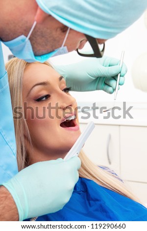 Dentist examines teeth of the patient on the dentist\'s chair