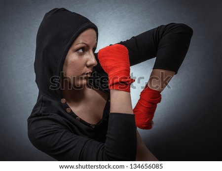 Hard sport woman ready for fight. Fighter girl with hoodie over dark gray background
