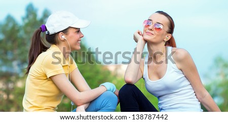 Friendship of smiling girl friends in sports clothing. Outdoors - outside
