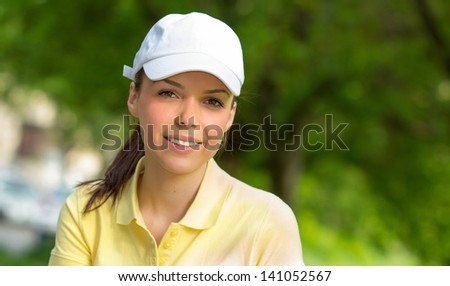 Portrait of a smiling young sports woman wearing cap, close-up face of fit girl, outdoors