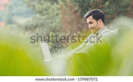Thoughtful young man with laptop, outdoor - outside. Side view sideways