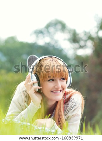 Beautiful young woman with headphones. Enjoy music outdoors. Girl repose or lie down relaxing