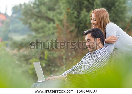 Couple or friends using laptop, outdoor - outside. Man web surfing internet with girlfriend