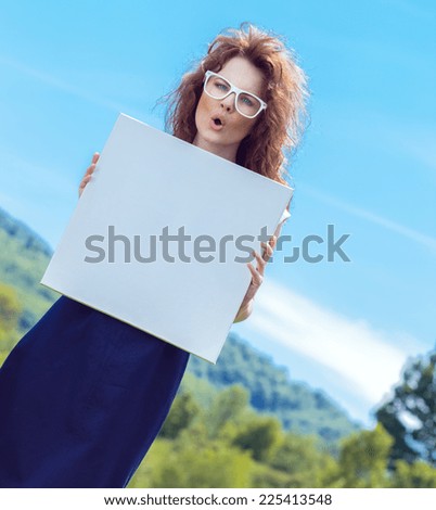 Expressive funny woman holding white board - copyspace. Outdoors