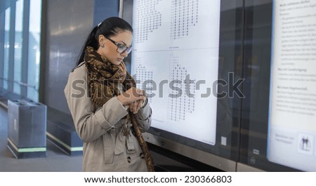 Woman or passenger - traveler showing the departure and arrival times of trains, buses