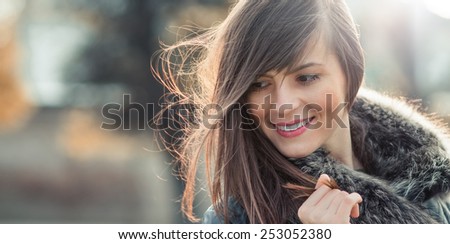 Woman with hair blowing in the wind with a blurred nature background, natural hairstyle. Outdoors with copyspace