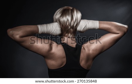 Sporty woman from behind showing her fists in bandage. Hard sport concept