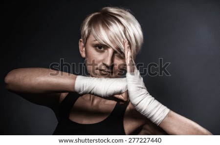 Woman showing her fists with bandage ready for fight. Close up boxer female on dark background
