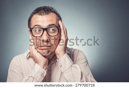 Close up of a  funny afraid businessman over gray background.\
\
Man in fear touching his face with hands.