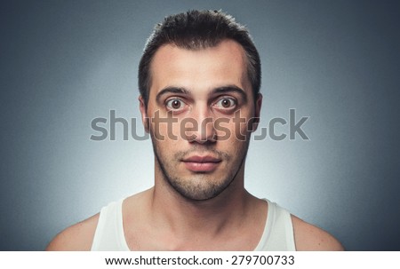 Big eyes of young man, Guy looking, close up head shot over dark gray background, studio shot