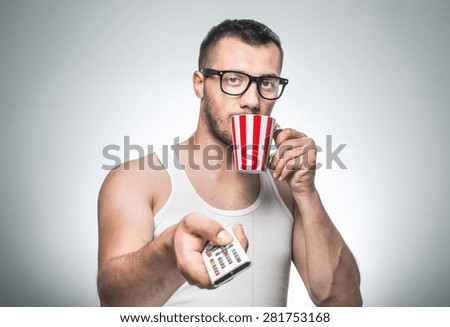Man with cup coffee and remote control leisure and watching TV.\
\
No stress, isolated on gray