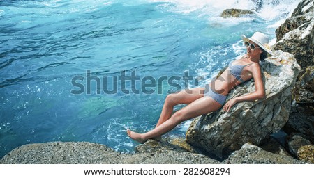 Young pretty woman on the beach sunbathing. Summer travel. Sea - water, wellbeing.\
\
Relaxed girl sunbathe in bikini wearing sunglasses and hat.  Copay space - copyspace