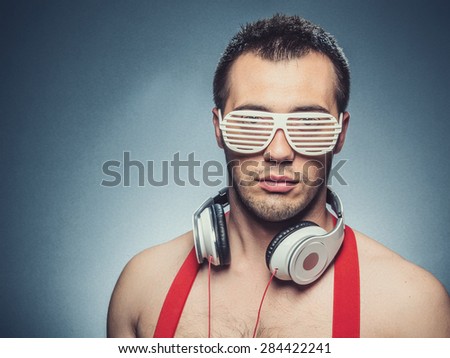 Party man, guy is ready for party. Young trendy man with headphones over dark blue gray background, studio shot