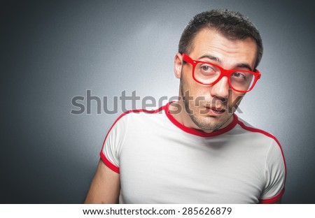 Confused young man. Close up portrait of nerd worried guy over gray dark background