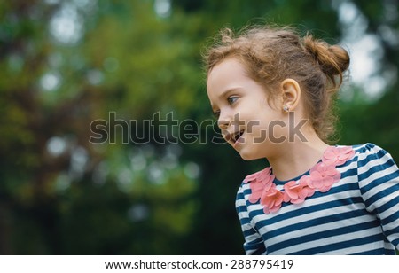 Profile of cute little girl in a park. Close-up of beautiful child, outdoors
