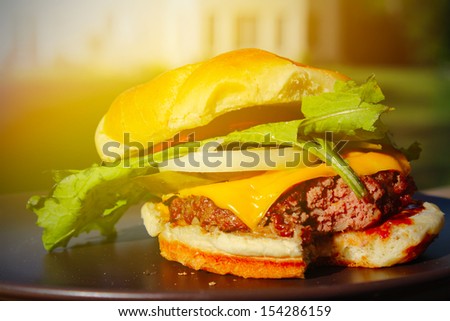 Delicious cheeseburger stacked high with a juicy beef patty, cheese, fresh lettuce, onion and tomato on a fresh bun with sesame seed
