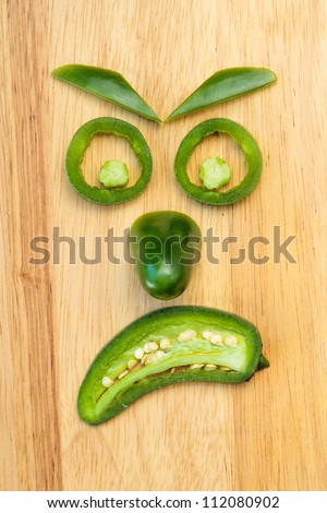 Face made of jalapeno pepper pieces showing the emotion of anger
