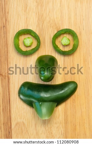 Face made of jalapeno pepper pieces showing the emotion of silliness with tongue sticking out