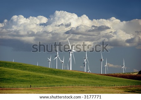 Stark White Electrical Power Generating Windmills on Rolling Hills, Beneath Summer Cumulus Clouds