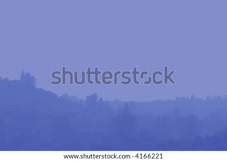 Abstract Background of Muted Blue Foothills and Pine Trees  in Heavy Fog and Mist