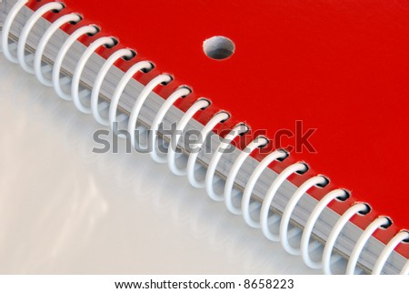 Close up of red spiral notebook on reflective surface.