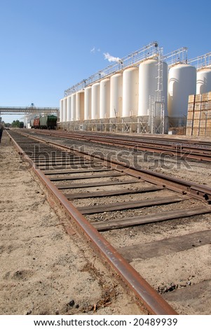 White tanks, rail cars, and railroad tracks, at industrial food processing plant