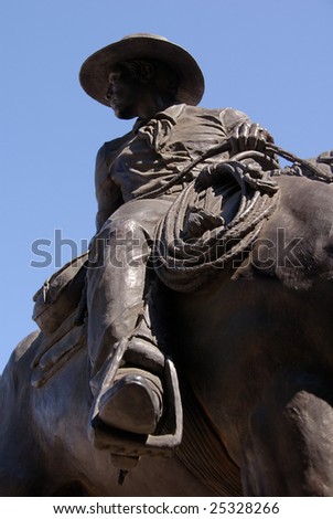 Public statue of bronze trail herder and horse honoring the American cowboy