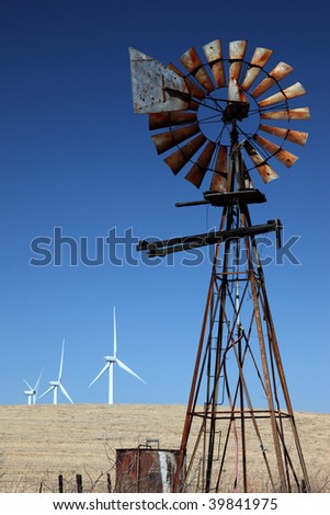 White power generating windmills behind a rusting agricultural ranch windmill.